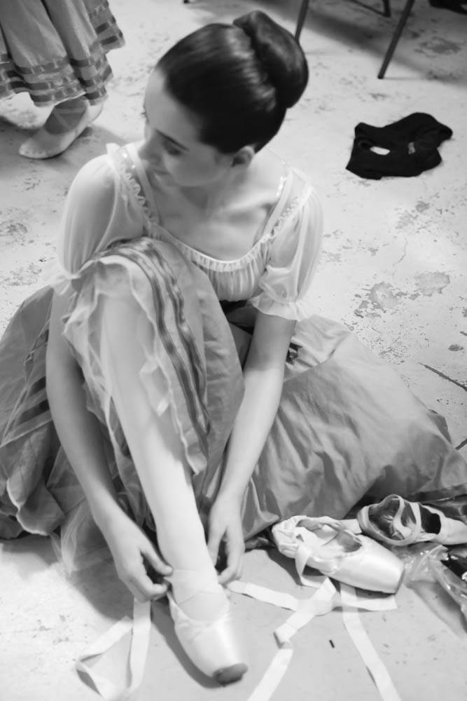 Ballerina putting on pointe shoes